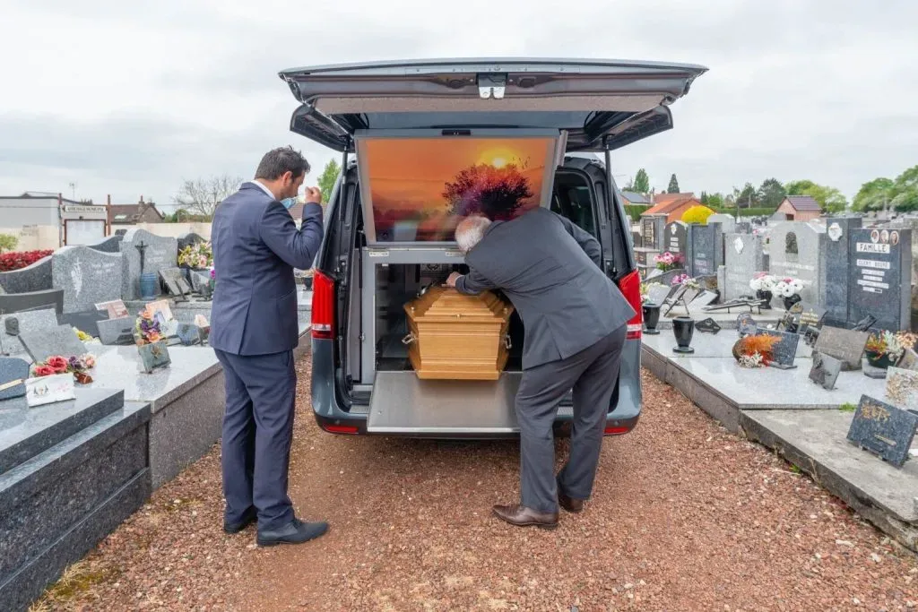 Cérémonie d'adieu au cimetière avec dépôt du cercueil dans le corbillard.
