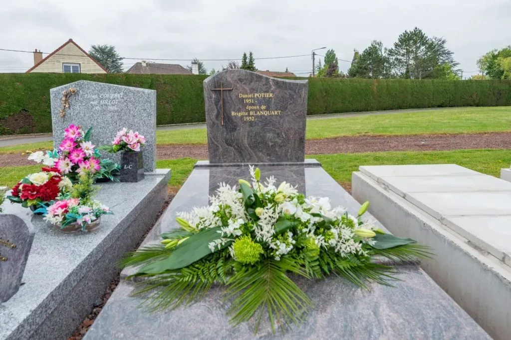 Tombe en marbre gris ornée d'un grand bouquet de fleurs fraîches.