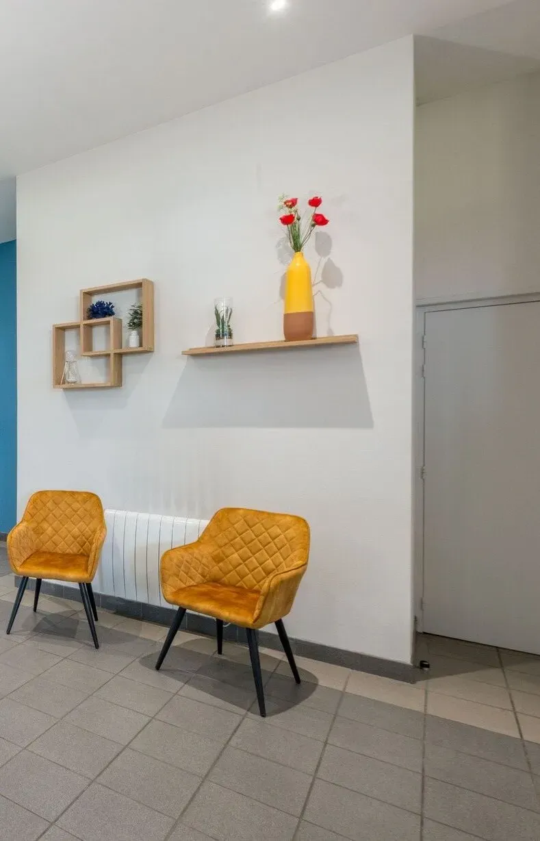 Coin d'attente convivial avec chaises jaunes et décoration murale.