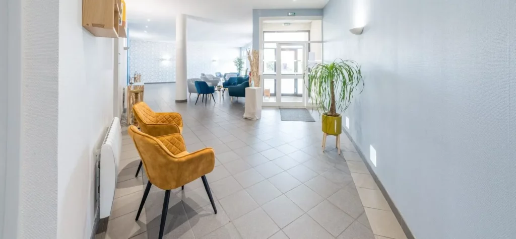 Couloir d'accès lumineux avec fauteuils design en velours jaune.